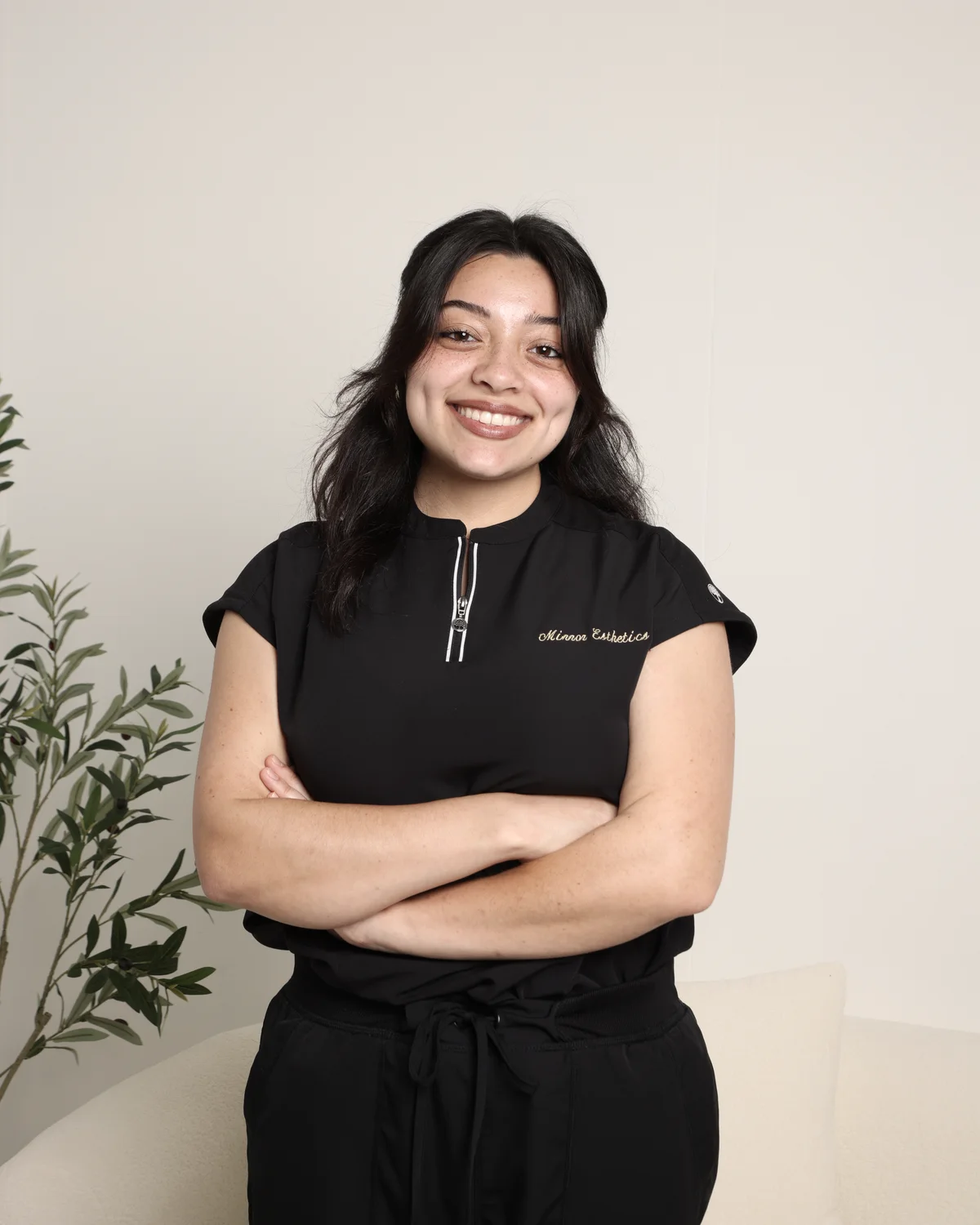 A Mirror Esthetics esthetician in uniform, arms folded, in the studio