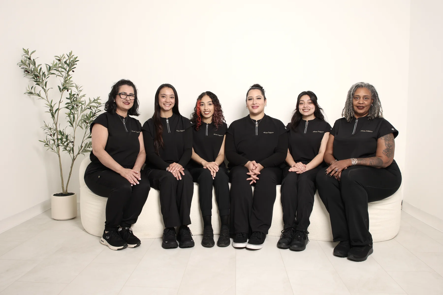Six members of the Mirror Esthetics team seated together in the studio