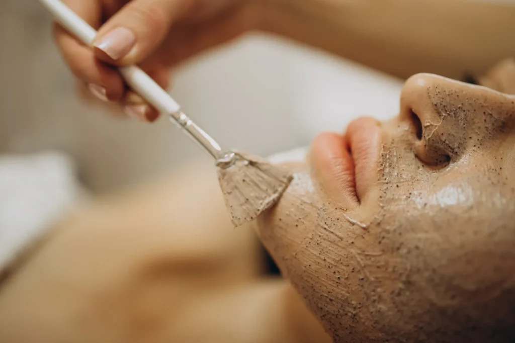 A facial exfoliating product being brushed onto the cheek.
