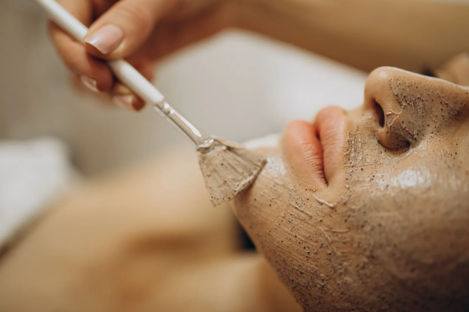 A facial exfoliating product being brushed onto the cheek.