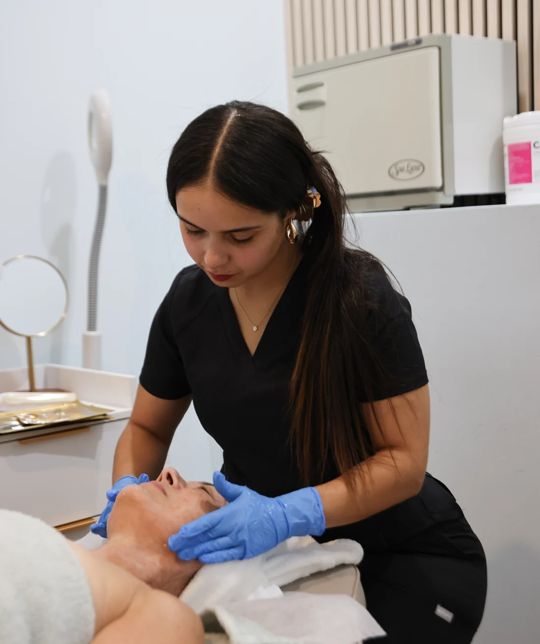 A Mirror Esthetics esthetician applying a facial treatment to a client in the studio