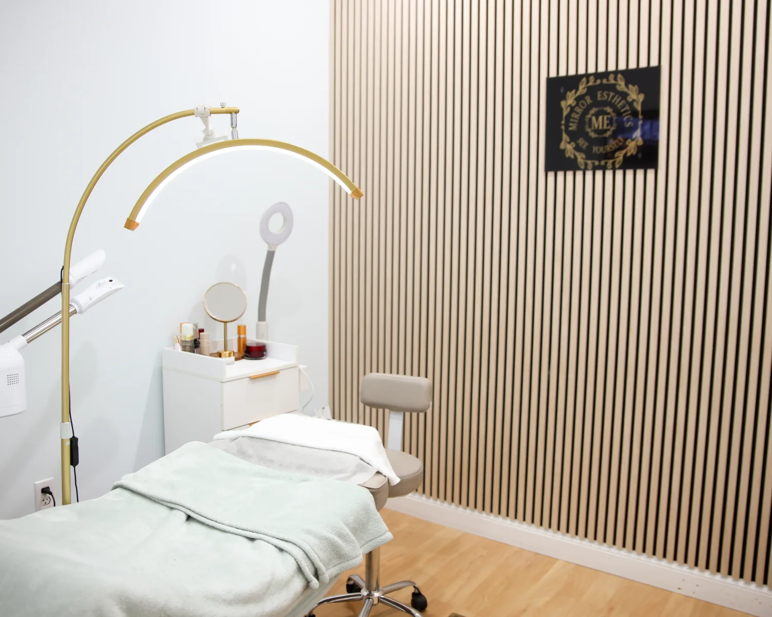 A Mirror Esthetics treatment room set up for a facial, with the LED arc light and treatment bed